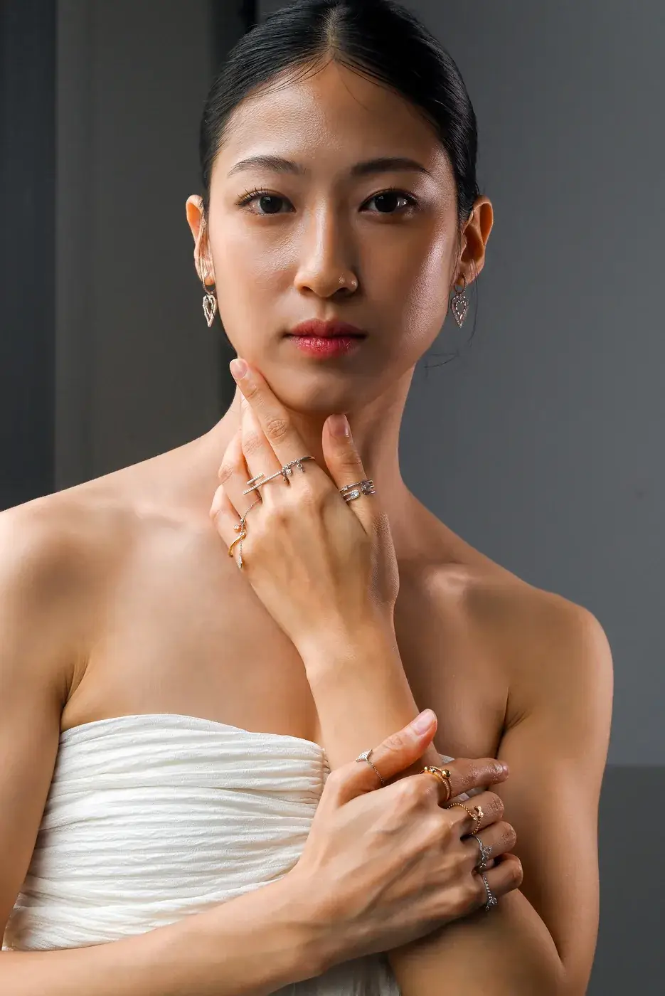 Model wearing stacked diamond rings and fine earrings